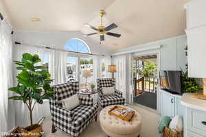 Living area featuring a healthy amount of sunlight, ceiling fan, light colored carpet, and lofted ceiling