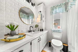 Bathroom featuring crown molding, vanity, brick wall, and toilet