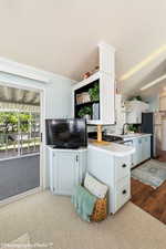 Kitchen with white cabinetry, sink, kitchen peninsula, stainless steel fridge, and light colored carpet