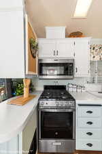 Kitchen featuring a textured ceiling, crown molding, white cabinetry, and stainless steel appliances