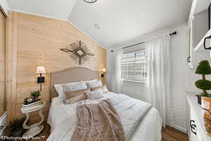 Bedroom featuring wooden walls, hardwood / wood-style floors, and lofted ceiling