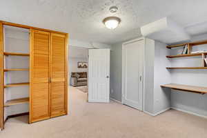 Unfurnished bedroom with a closet, light colored carpet, and a textured ceiling