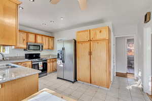 Kitchen featuring light brown cabinetry, sink, light tile patterned floors, and appliances with stainless steel finishes