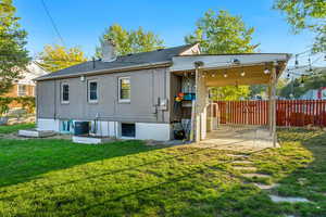 Back of property featuring central air condition unit and a yard