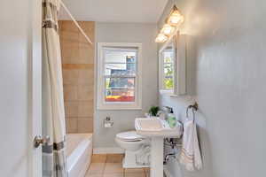 Bathroom with tile patterned flooring, shower / bath combination with curtain, and toilet