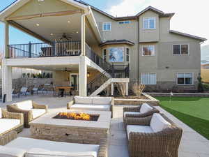 Back of house with a balcony, patio area, and an outdoor living space with a fire pit