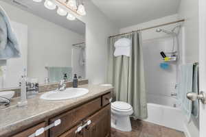 Full bathroom featuring vanity, toilet, a textured ceiling, and shower / tub combo