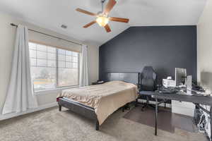 Carpeted bedroom featuring vaulted ceiling and ceiling fan