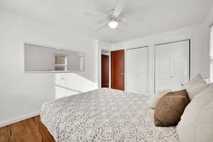 Bedroom with hardwood / wood-style flooring, ceiling fan, and two closets