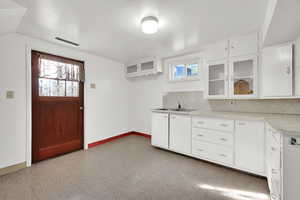 Kitchen featuring white cabinetry, sink, and tasteful backsplash