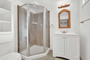 Bathroom featuring tile patterned flooring, vanity, toilet, and a shower with shower door