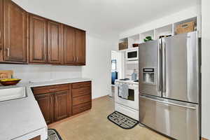 Kitchen with dark brown cabinetry, white appliances, and sink