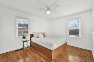 Bedroom featuring multiple windows, hardwood / wood-style flooring, and ceiling fan