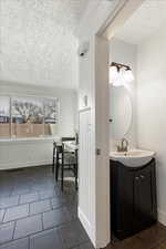 Bathroom featuring tile patterned flooring, vanity, and a textured ceiling