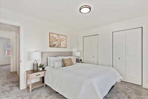 Carpeted bedroom with ornamental molding and two closets