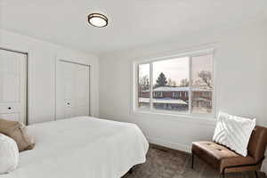 Carpeted bedroom with two closets, ornamental molding, and multiple windows