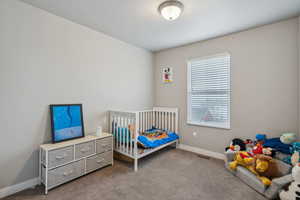 Bedroom featuring light colored carpet and a crib