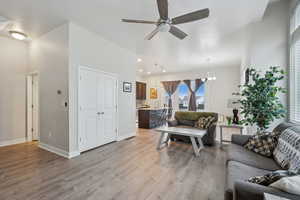 Living room with light hardwood / wood-style floors and ceiling fan with notable chandelier