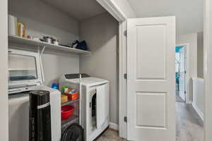 Laundry room with washing machine and dryer and light hardwood / wood-style floors