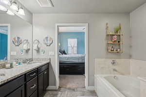 Bathroom featuring tile patterned floors, a relaxing tiled tub, and vanity