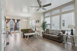 Living room featuring a healthy amount of sunlight, ceiling fan with notable chandelier, and hardwood / wood-style flooring