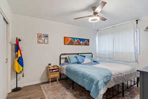 Bedroom with ceiling fan, dark wood-type flooring, and a closet