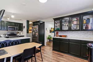 Kitchen with appliances with stainless steel finishes, tasteful backsplash, and light hardwood / wood-style flooring