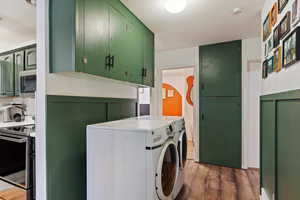 Clothes washing area with dark hardwood / wood-style flooring and washer and clothes dryer