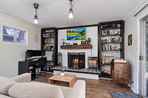 Living room with a fireplace, hardwood / wood-style flooring, and crown molding