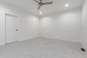 Empty room with ceiling fan and light carpet