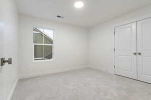 Unfurnished bedroom featuring light colored carpet and a closet