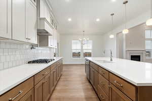 Kitchen with white cabinets, sink, a brick fireplace, appliances with stainless steel finishes, and decorative light fixtures