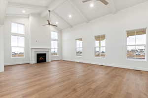 Unfurnished living room featuring beam ceiling, light hardwood / wood-style flooring, and high vaulted ceiling