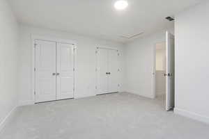 Unfurnished bedroom with light carpet and two closets