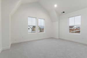 Additional living space with light carpet and lofted ceiling