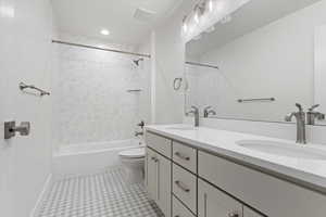 Full bathroom featuring tiled shower / bath combo, toilet, and vanity