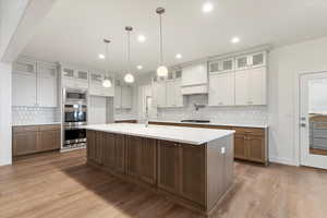 Kitchen featuring white cabinets, pendant lighting, stainless steel appliances, and a kitchen island with sink