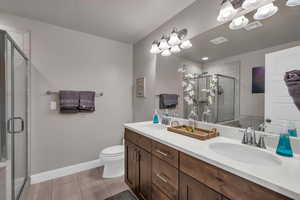 Bathroom featuring tile patterned floors, vanity, an enclosed shower, and toilet