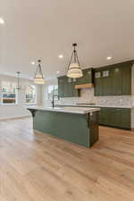 Kitchen with sink, light hardwood / wood-style flooring, hanging light fixtures, and green cabinetry