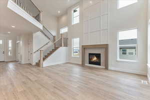 Unfurnished living room featuring a towering ceiling and light hardwood / wood-style flooring