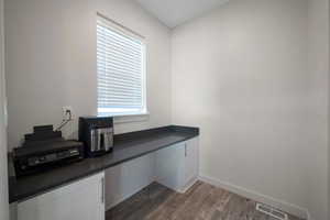 Office area featuring built in desk, dark hardwood / wood-style floors, and plenty of natural light