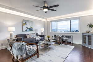 Living room with ceiling fan and dark wood-type flooring