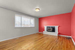 Unfurnished living room featuring a wood stove and hardwood / wood-style flooring