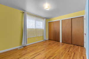 Unfurnished bedroom with two closets and light hardwood / wood-style flooring