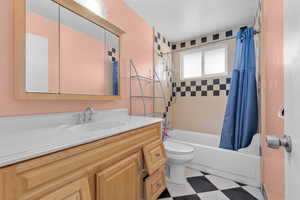 Full bathroom featuring shower / bath combination with curtain, toilet, and vanity