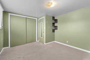 Unfurnished bedroom with light carpet and a closet