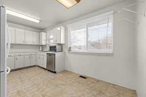 Kitchen featuring white cabinets, white refrigerator, stainless steel dishwasher, and sink