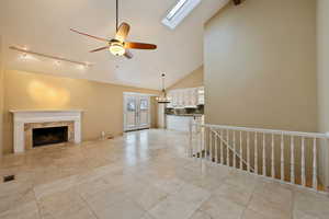 Family room featuring high vaulted ceiling, french doors, a skylight, ceiling fan, and a fireplace