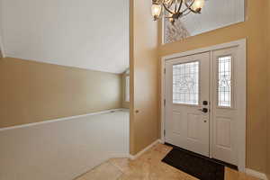 Entryway with light carpet, lofted ceiling, and an inviting chandelier