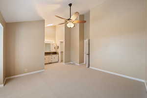 Owner's bedroom featuring ceiling fan, light colored carpet, ensuite bathroom, and high vaulted ceiling